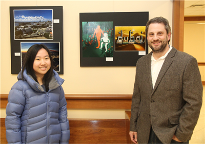  student and teacher standing in front of art display